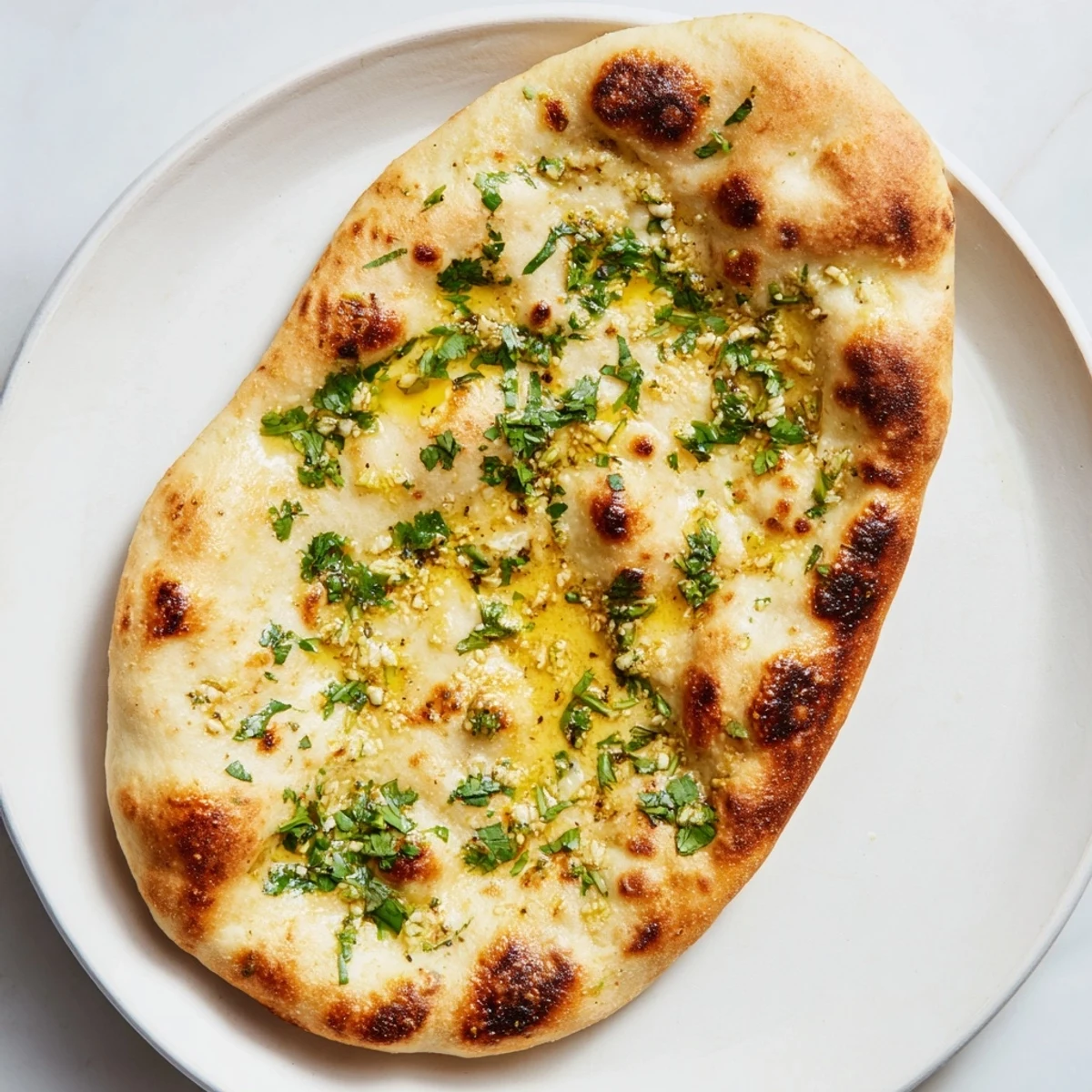 Fluffy, golden-brown garlic naan bread, speckled with fresh cilantro, ready to be served.