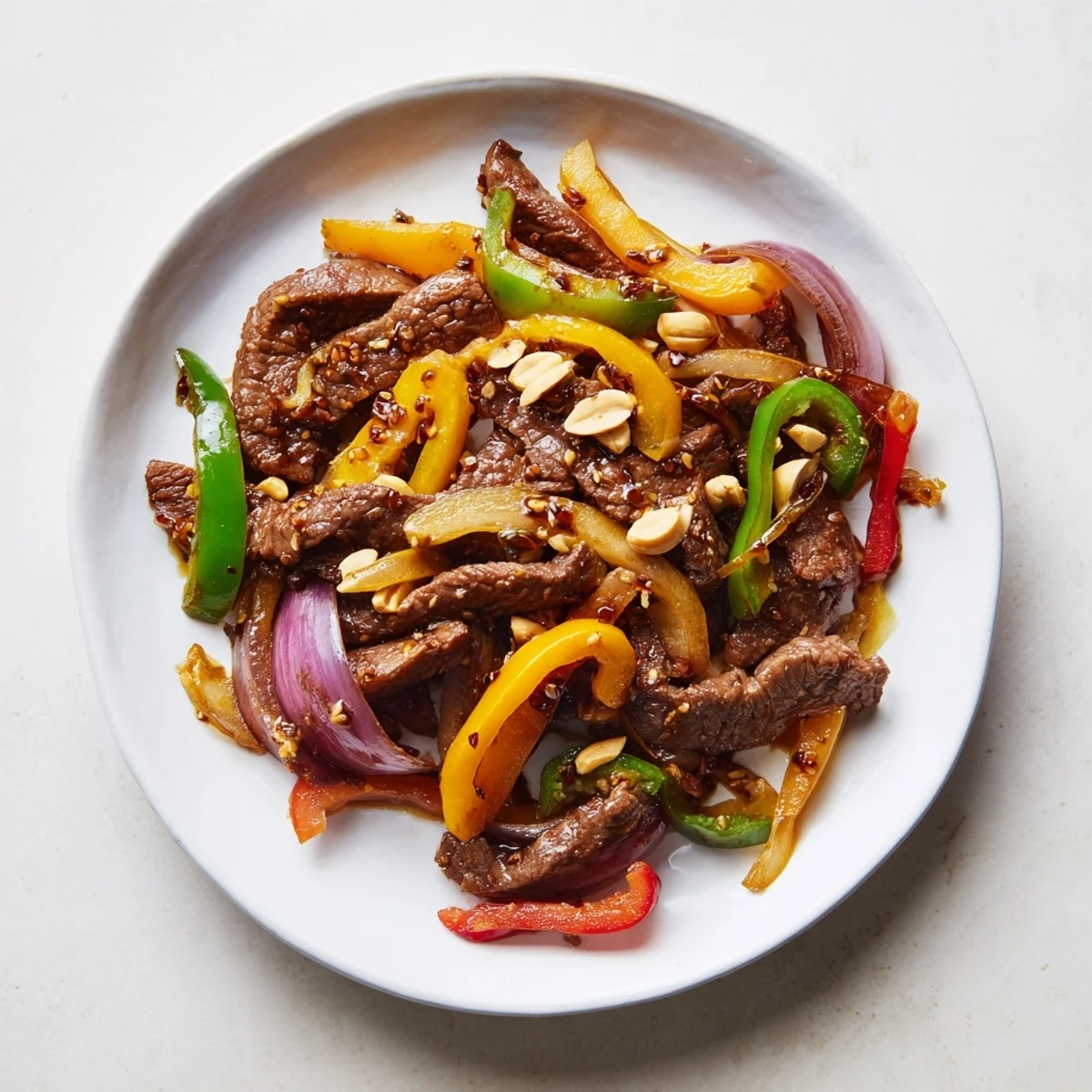 A steaming plate of Szechuan Beef, coated in a glistening sauce and sprinkled with optional peanuts.
