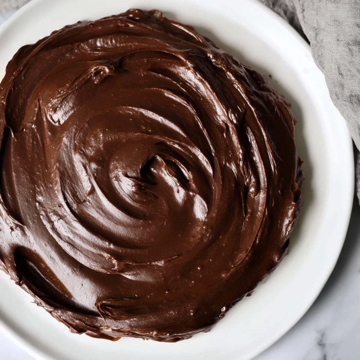 Velvety dark chocolate ganache, perfect dessert frosting, ready to be spread lavishly across a cake.