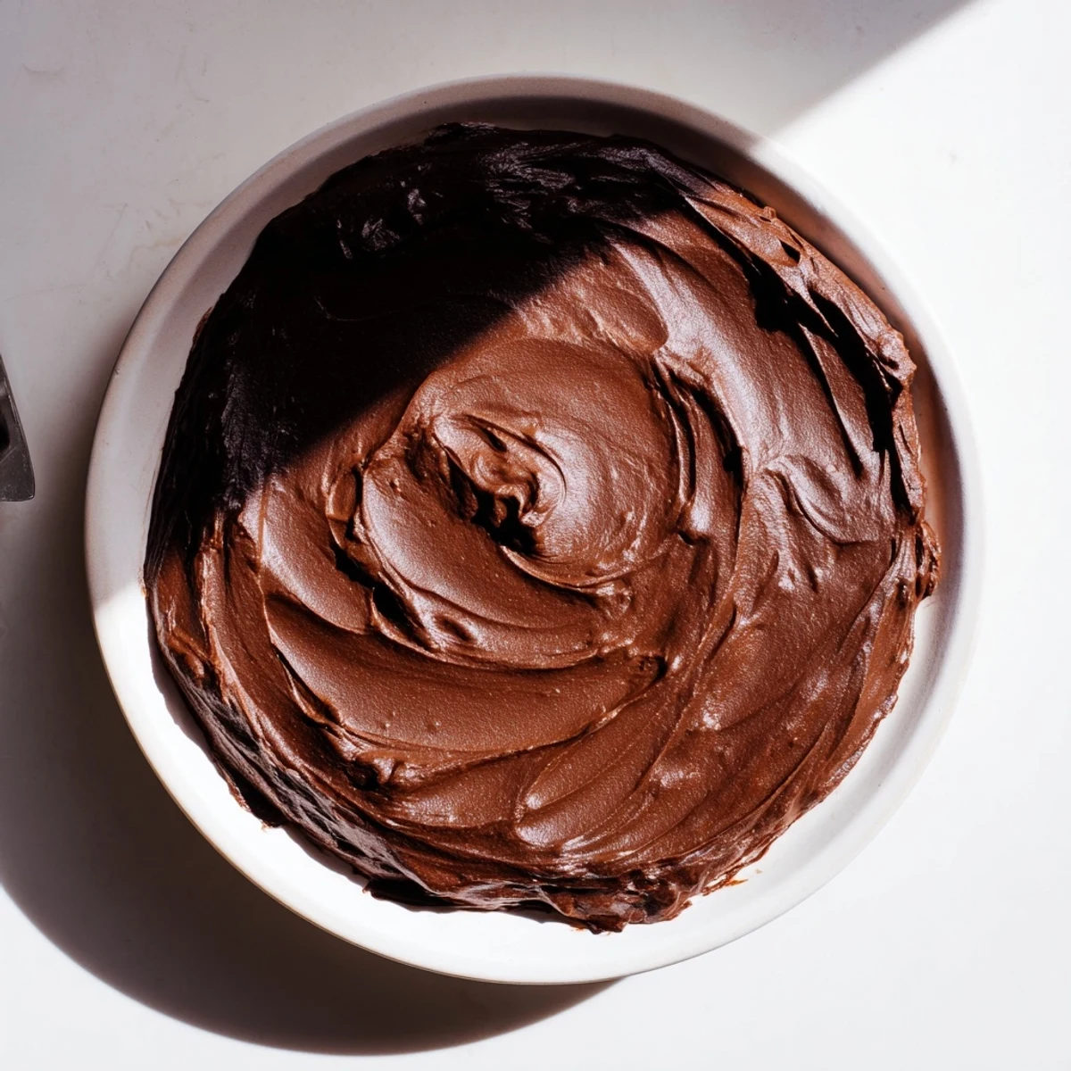 A luscious swirl of warm, glossy chocolate ganache, ideal for truffle-making or dessert enjoyment.