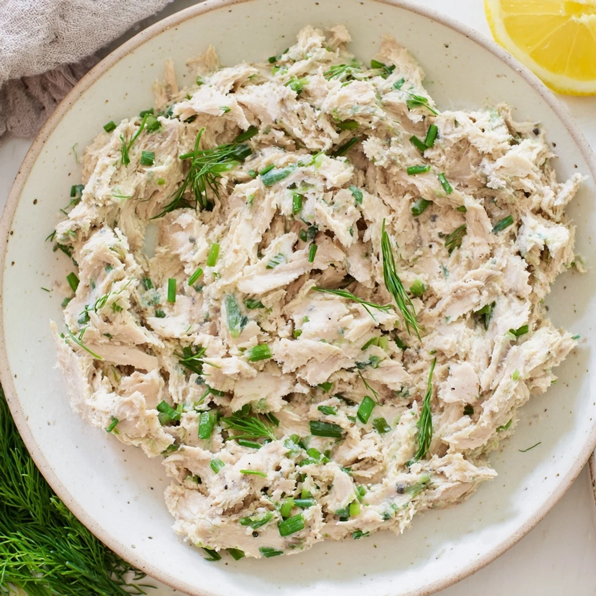 Close-up of a rustic smoked mackerel pâté, speckled with herbs, ready to be spread on toast.