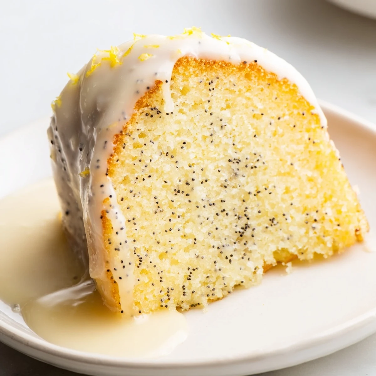Moist lemon poppy seed Bundt cake, topped with a sweet, drizzly glaze ready for serving.