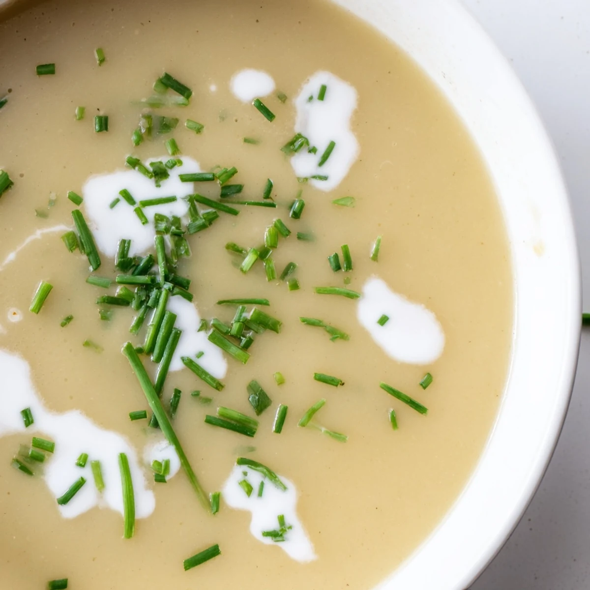 Creamy Potato Leek Soup with Chives served steaming hot in a rustic bowl, garnished with fresh chives and a swirl of rich cream.