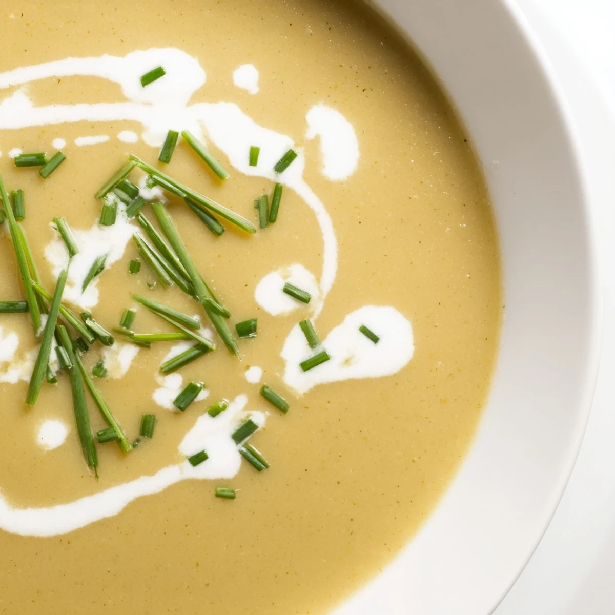 A bowl of Creamy Potato Leek Soup with Chives, thick and velvety, beside crusty artisan bread for a cozy vegetarian lunch.
