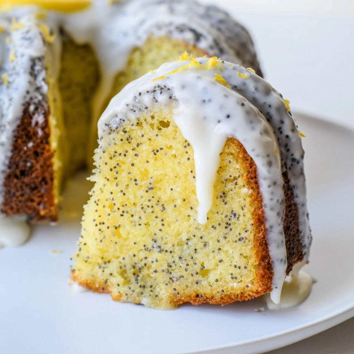 Close-up slice of Lemon Poppy Seed Bundt Cake with Glaze on a fork, revealing a moist crumb speckled with poppy seeds.