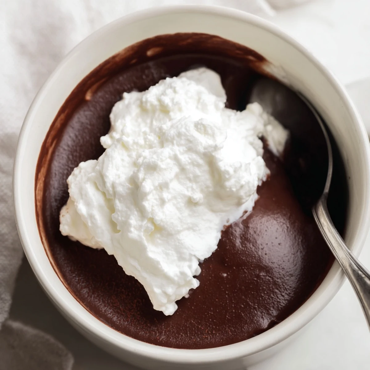Velvety chocolate pudding with homemade whipped cream, served chilled in individual dishes and ready for a chocolate shaving garnish. 