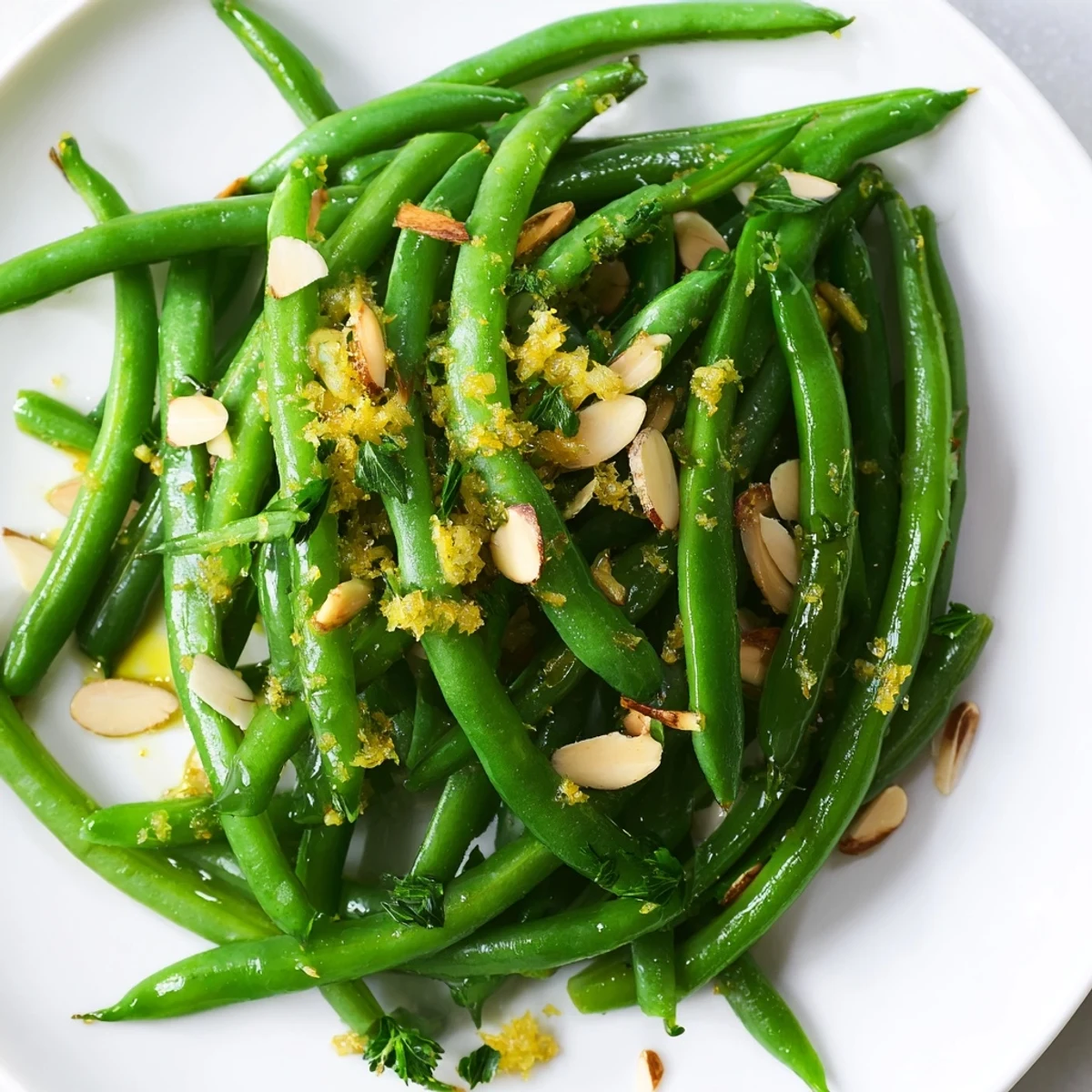 Golden sliced almonds and fresh parsley top a serving of Lemon Green Beans cooked with olive oil and garlic.