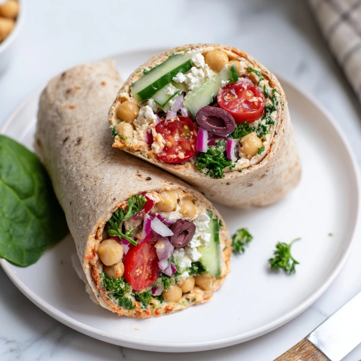 Homemade Mediterranean Chickpea Wrap with mashed chickpeas and fresh parsley, sliced in half to reveal the colorful, hearty filling.