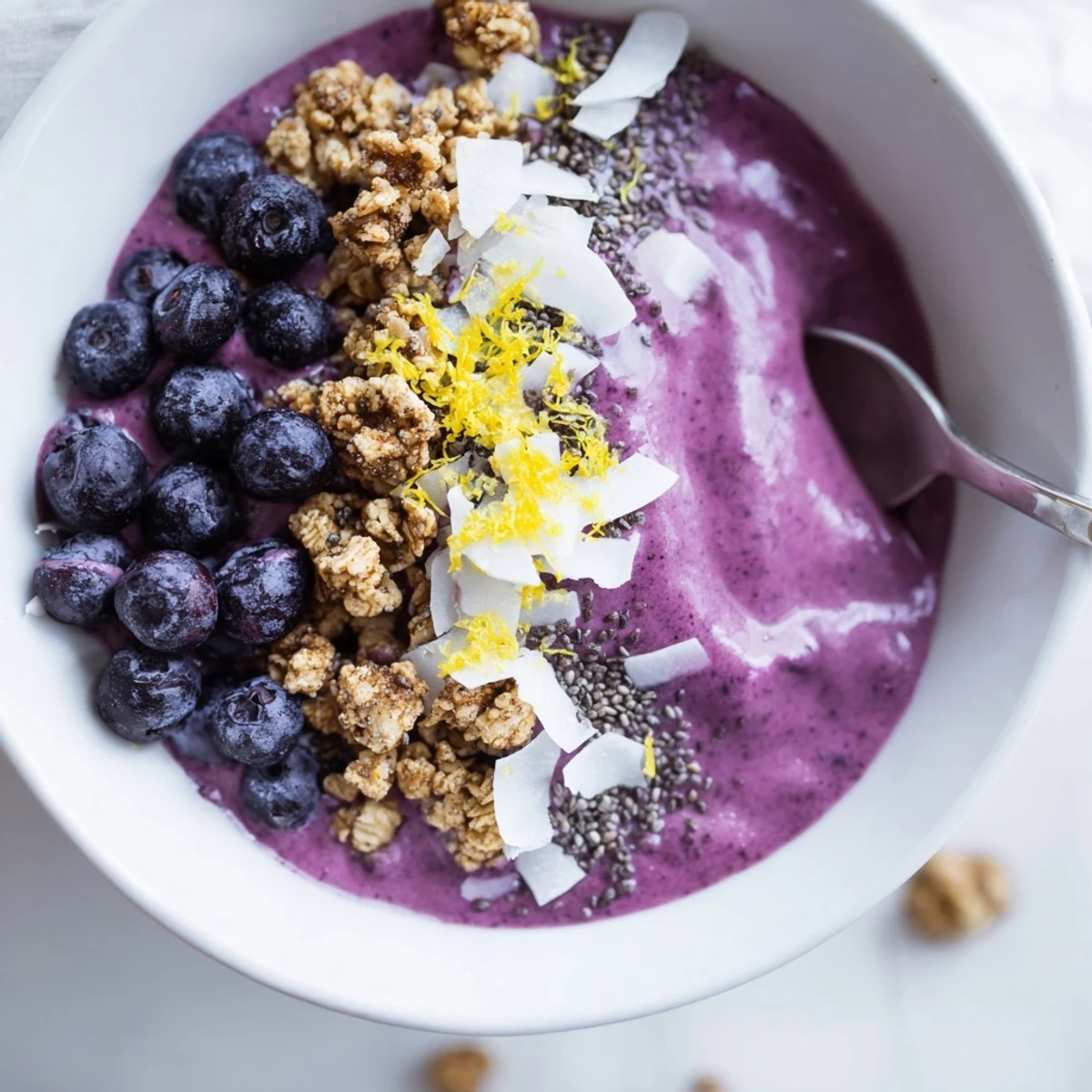 Thick and creamy Lemon Blueberry Smoothie Bowl with a bright swirl of lemon zest and crunchy granola toppings in a rustic bowl.