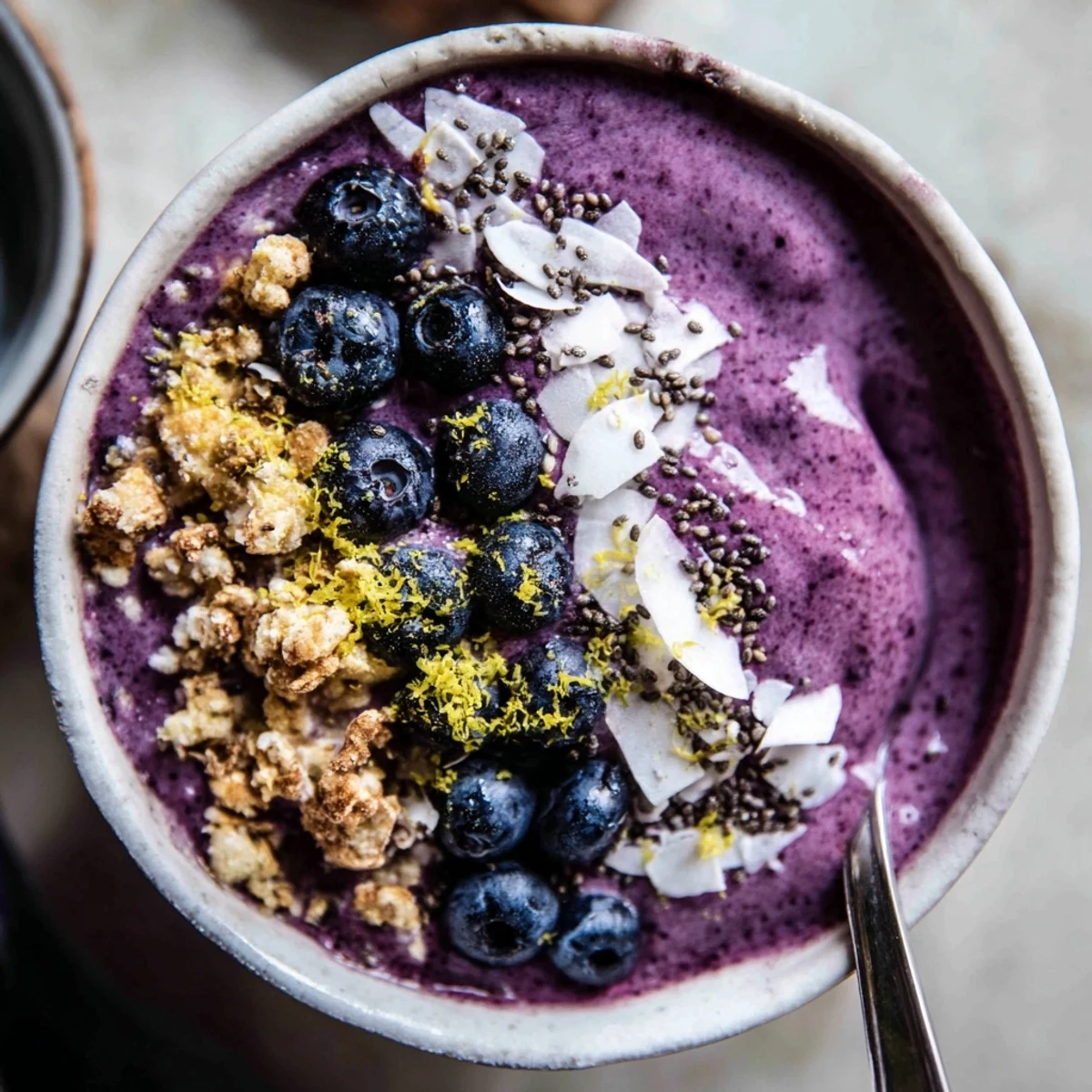 Refreshing Lemon Blueberry Smoothie Bowl served with almond milk yogurt, shredded coconut, and chia seeds for a perfect morning boost.