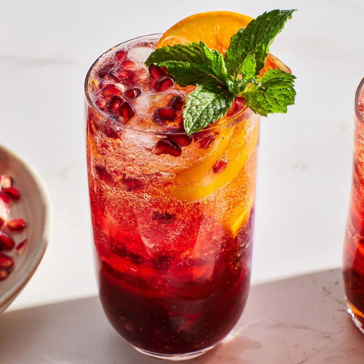 Love Potion Pomegranate Mocktail Fizz in chilled glasses garnished with fresh mint and lime slices.