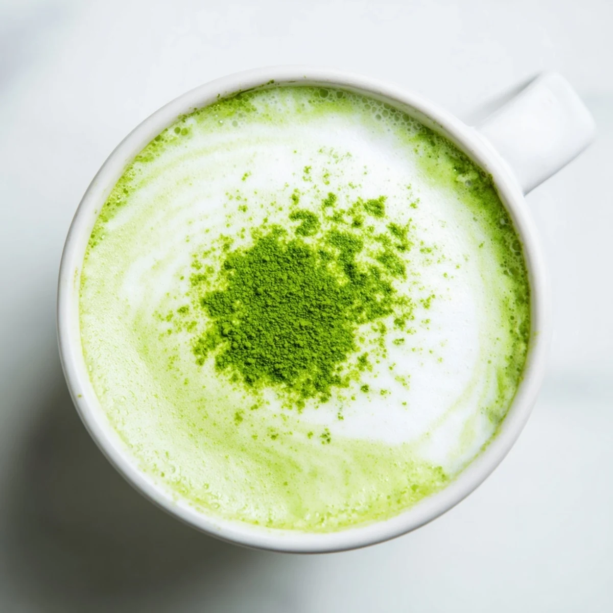 Frothy Shamrock Green Matcha Latte with honey being poured into a clear glass mug, revealing a creamy, festive emerald swirl.