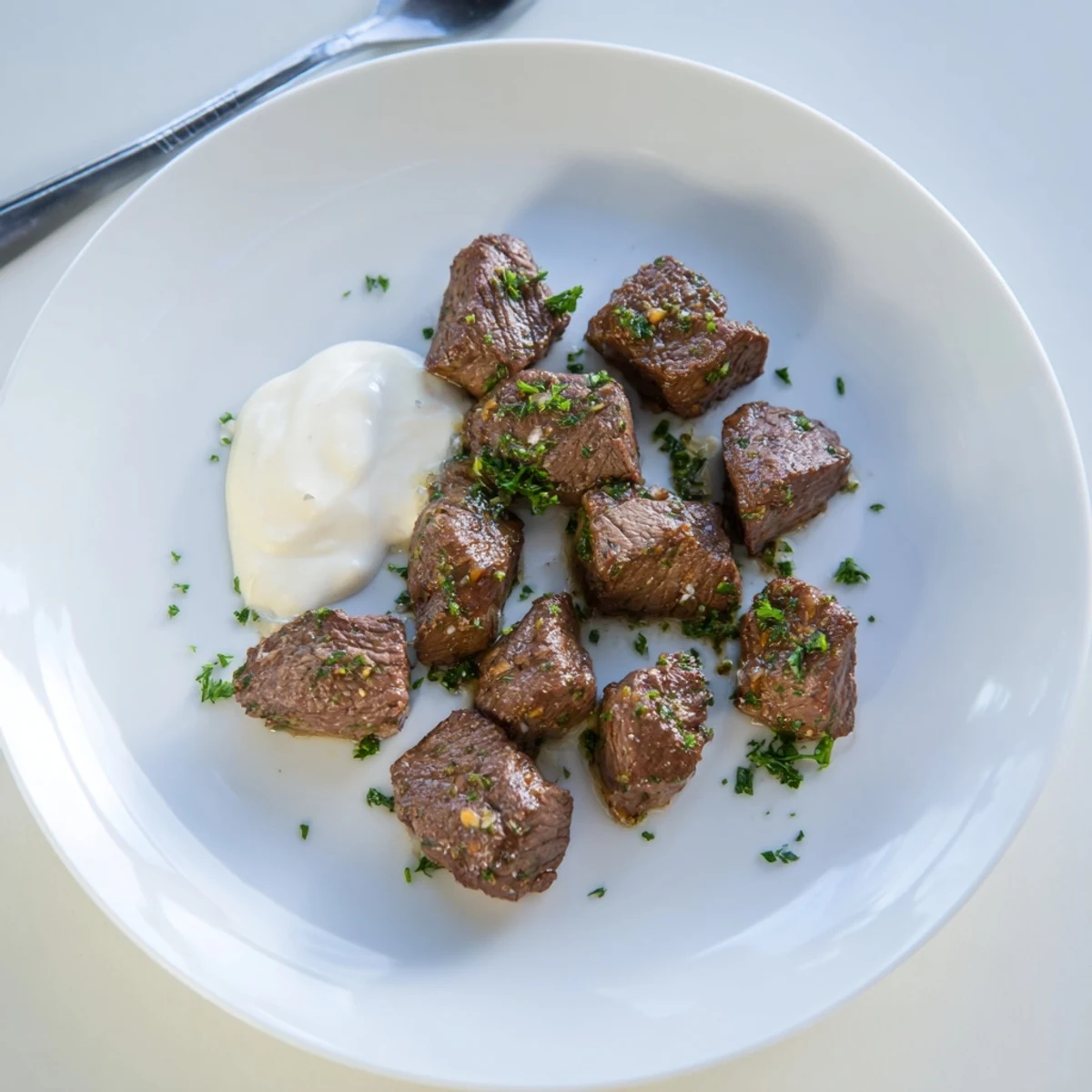 Golden-brown Garlic Butter Steak Bites sizzling in a skillet, garnished with fresh parsley and served beside a bowl of creamy horseradish sauce.  