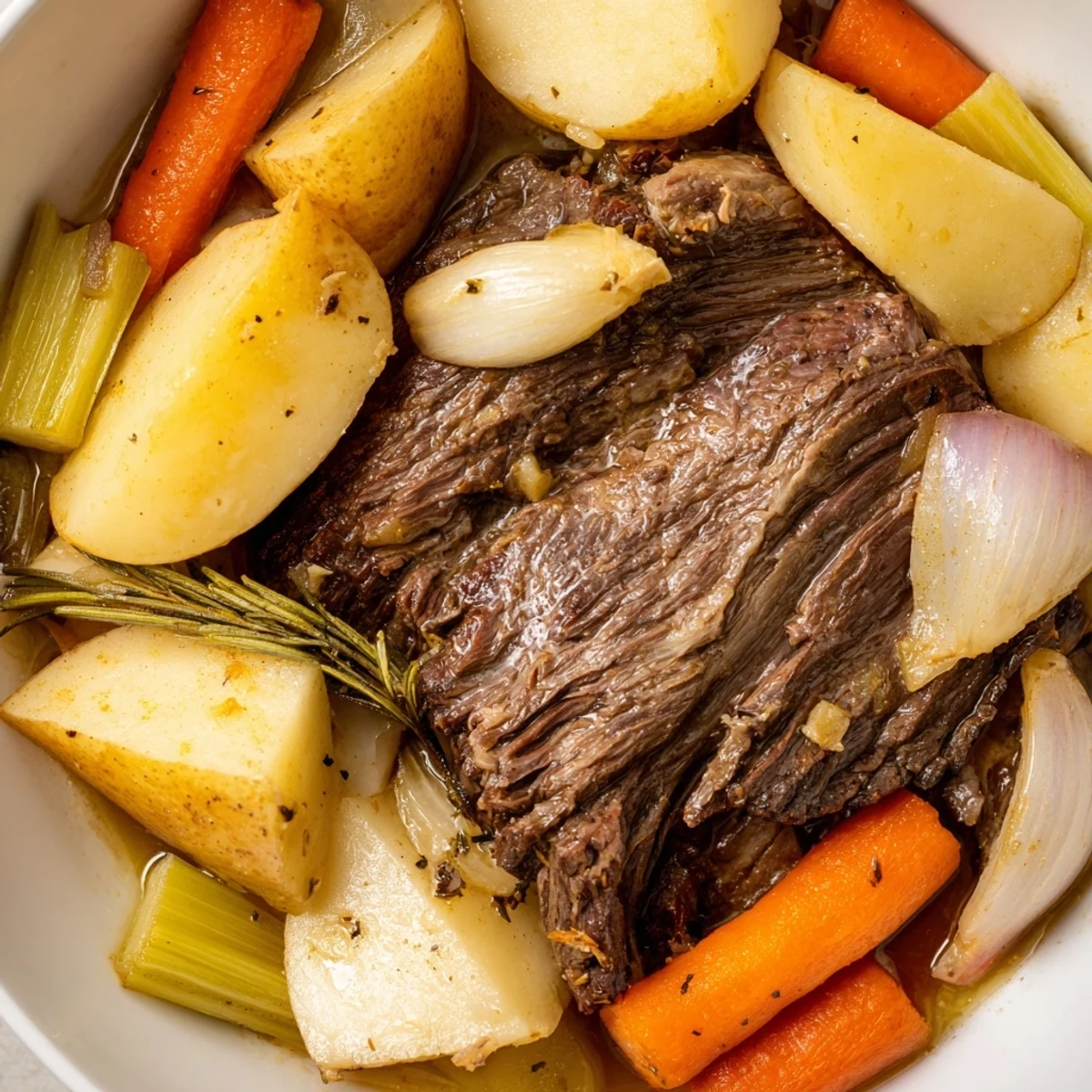 Fork-tender Slow Cooker Beef Pot Roast with Root Vegetables served in a savory broth alongside carrots and potatoes.
