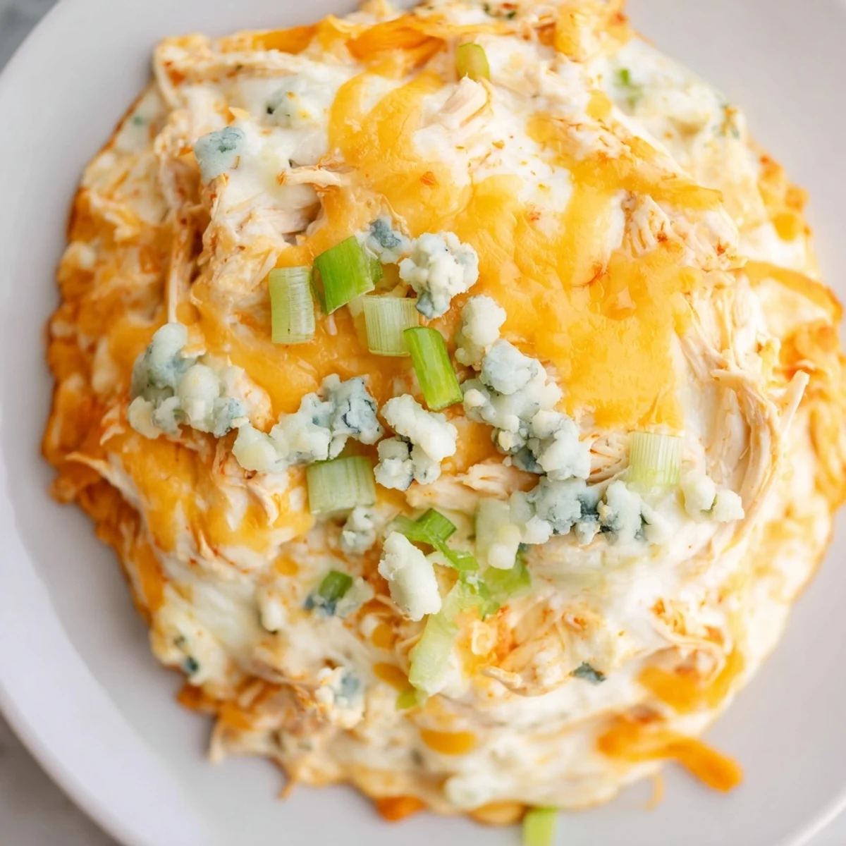 A close-up of creamy Keto Buffalo Chicken Dip with shredded chicken, melty cheddar, and spicy buffalo sauce, ready to dip.