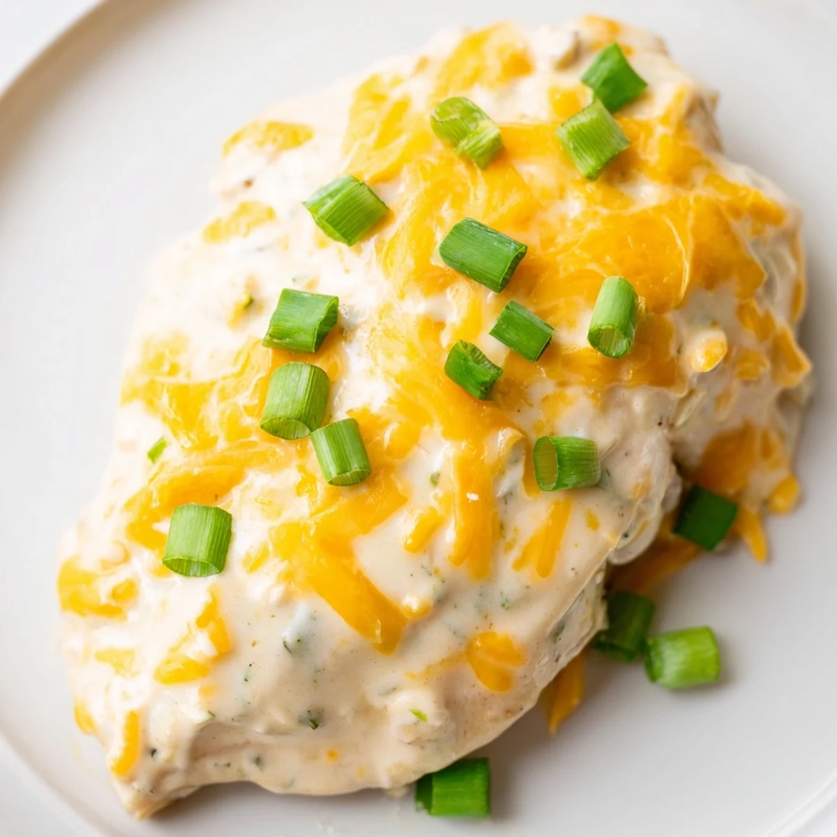 A close-up of sour cream and onion chicken topped with melted cheddar and crunchy gluten-free crackers, served alongside fluffy mashed potatoes.