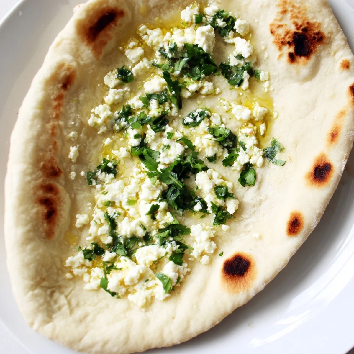 Homemade Cottage Cheese Garlic Naan topped with garlic butter, perfect alongside Indian curry dishes.