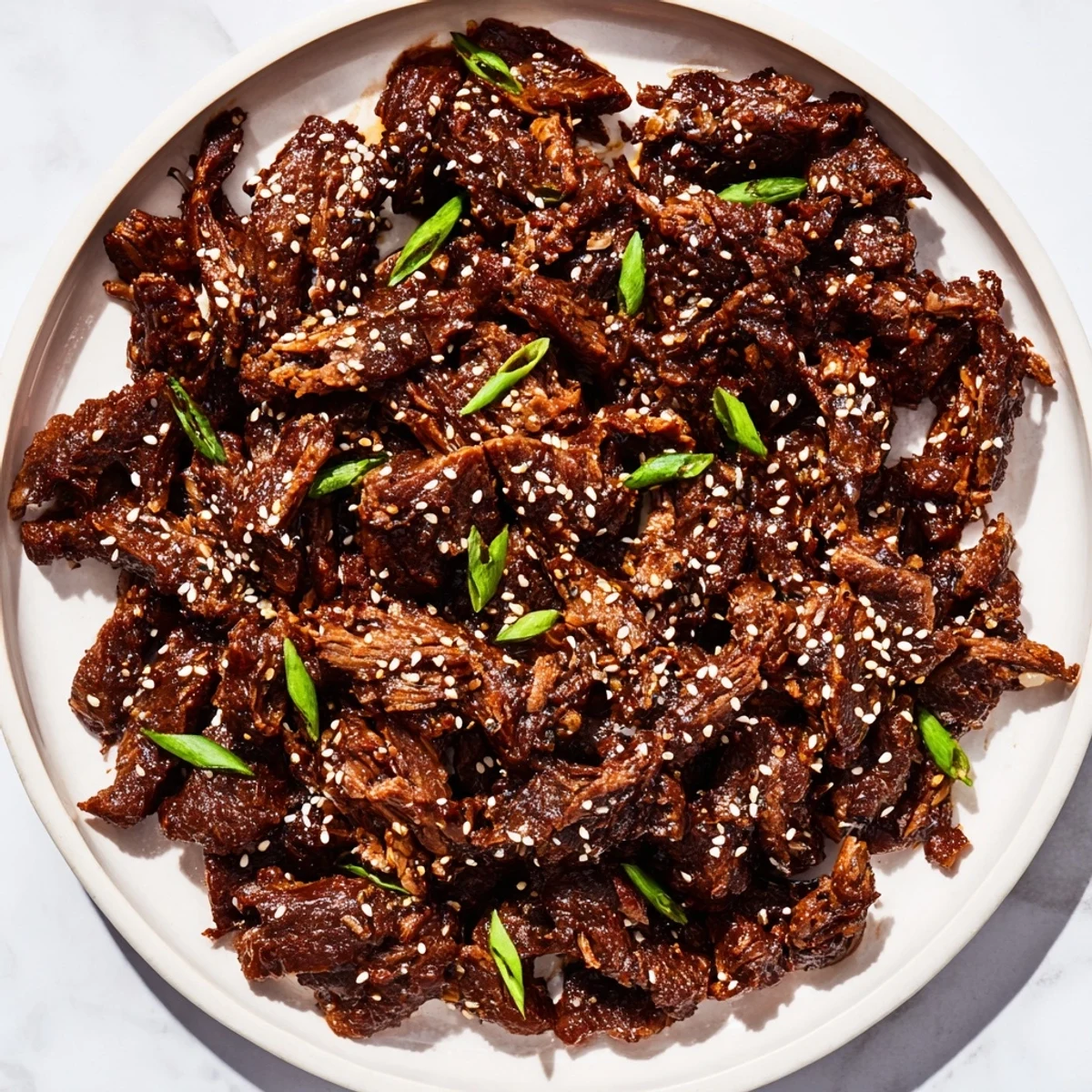 A close-up of Slow Cooker Korean Beef in a lettuce wrap, showcasing tender meat, spicy gochujang glaze, and a sprinkle of fresh green onions.