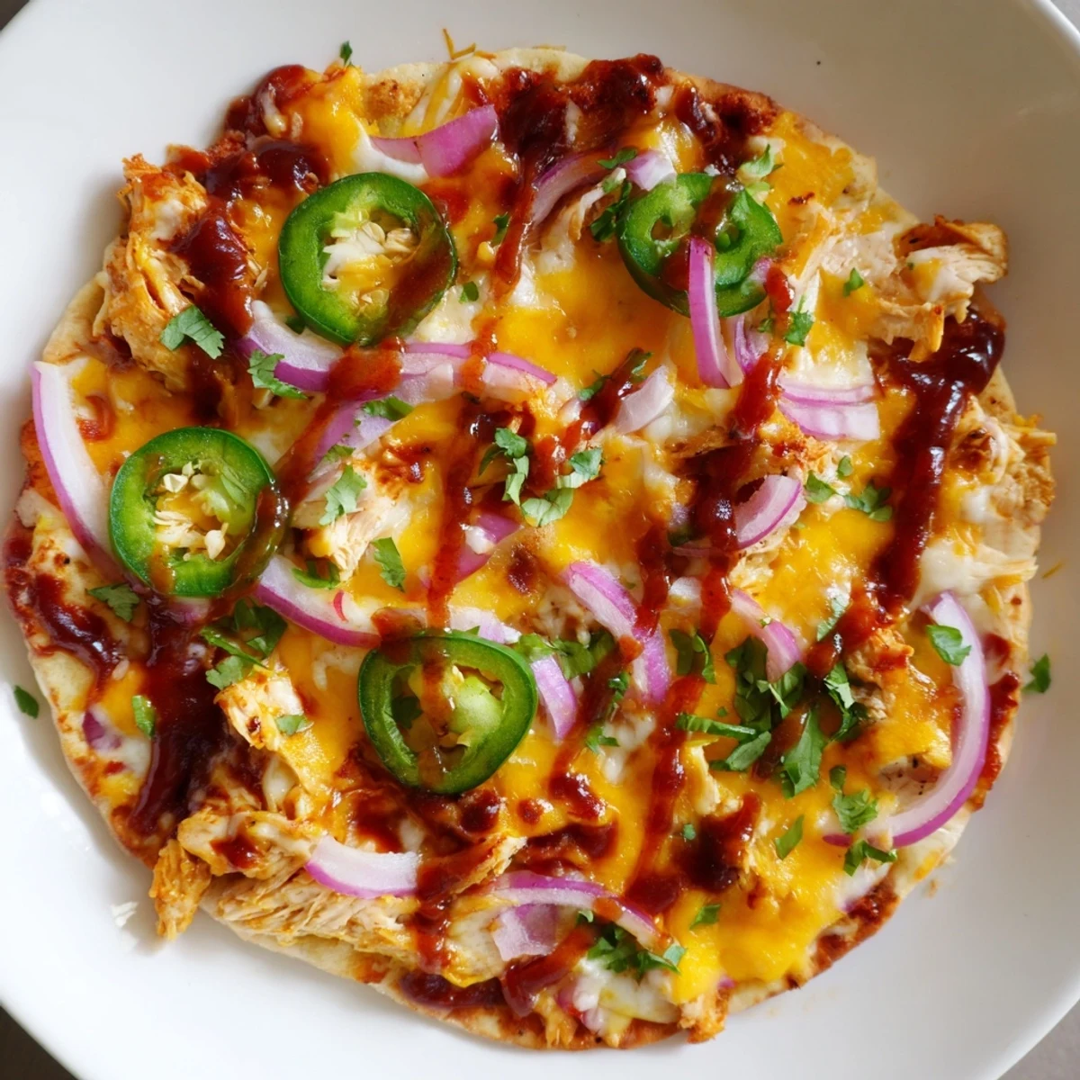 Savory BBQ Chicken Flatbread baked until bubbly and golden, drizzled with extra sauce and garnished with chopped cilantro for serving.