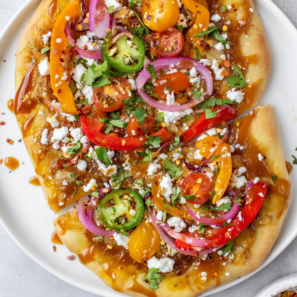 Golden-baked Sweet Heat Honey Garlic Flatbread Pizza with melted mozzarella and crumbled feta cheese topped with red onion and jalapeños.