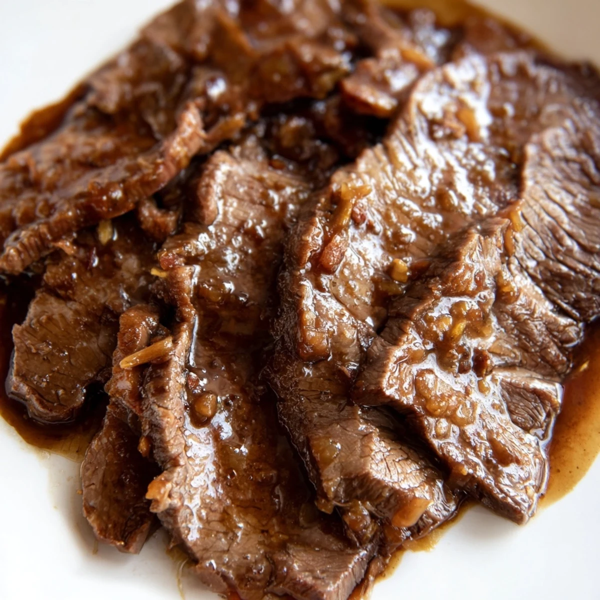 Ultimate Slow Cooker Mongolian Beef simmering in a rich brown sauce, served over fluffy white rice with chopsticks.