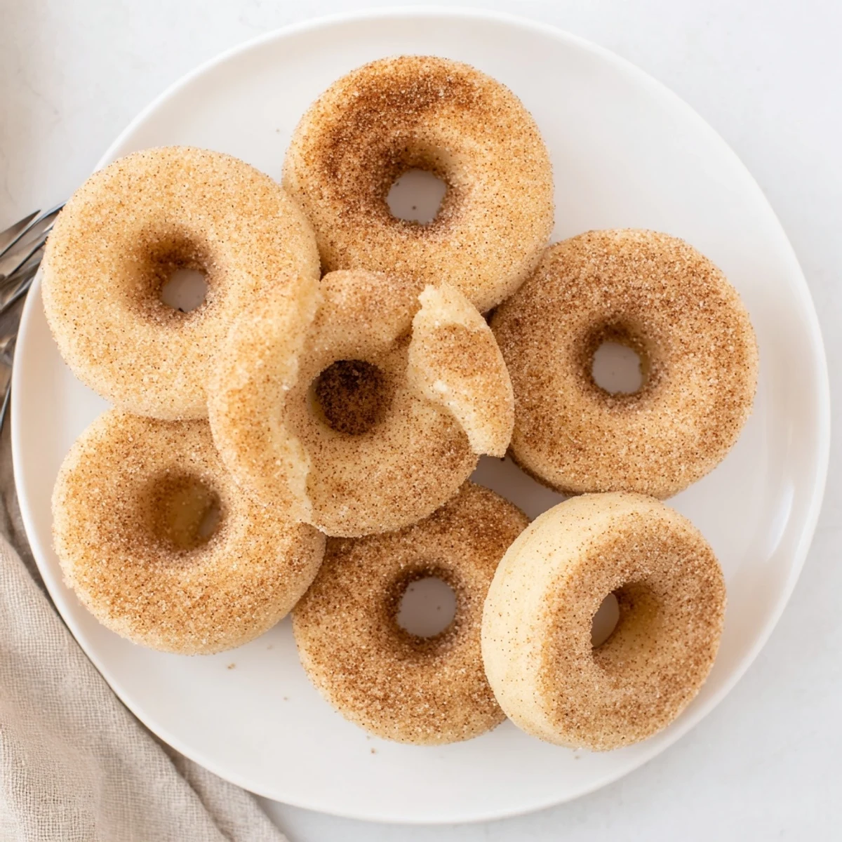 Freshly baked Delicious Baked Cinnamon Sugar Donuts You Cant Resist displayed on a wire cooling rack, coated in sparkling sugar.