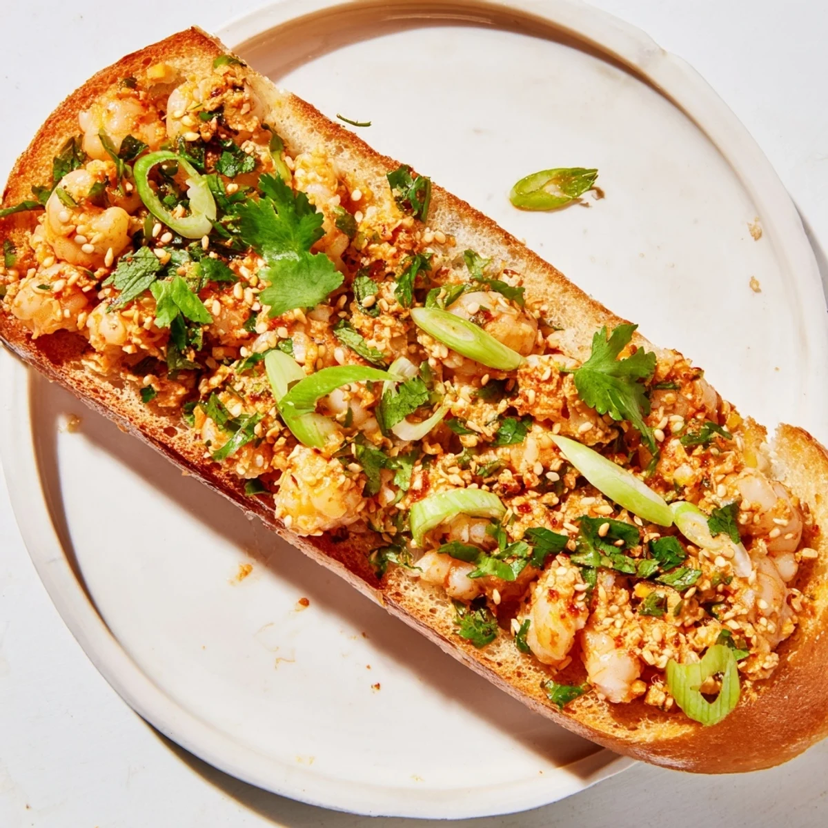 Golden toasts from a Vietnamese Cajun Shrimp Toast appetizer, stacked on a wooden board with limes and herbs for a party platter.
