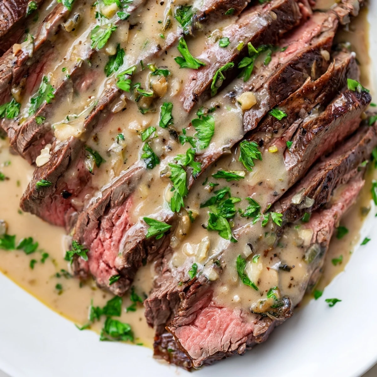 A plate of flank steak with roasted garlic sauce, garnished with parsley.
