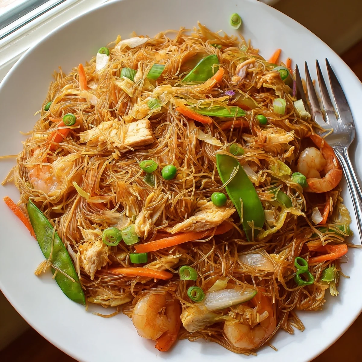 Sizzling Traditional Pancit Bihon stir-fry with vermicelli noodles crisp veggies and seafood served family-style