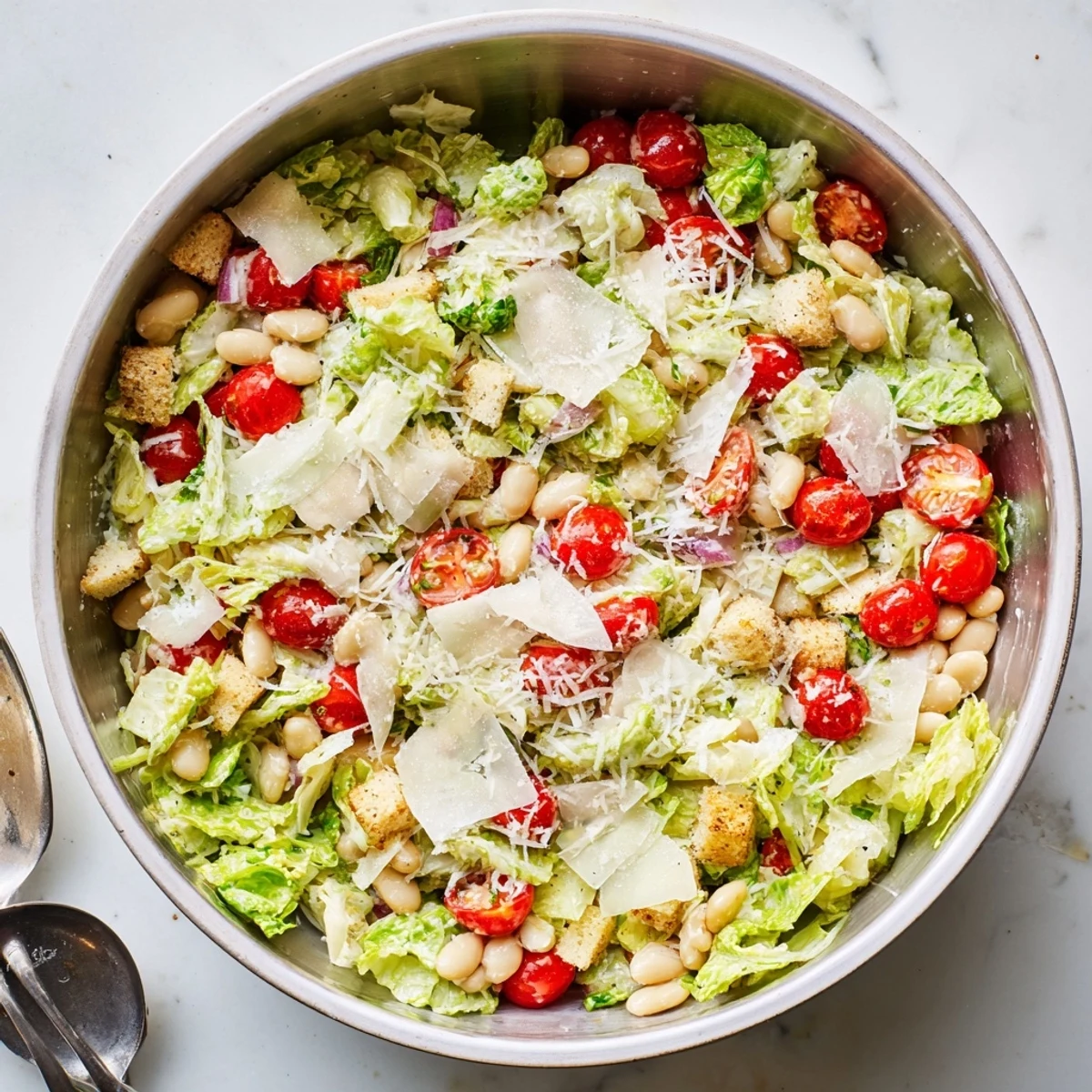 Fresh butter bean Caesar salad with crisp romaine, shaved Parmesan and golden croutons in a white bowl