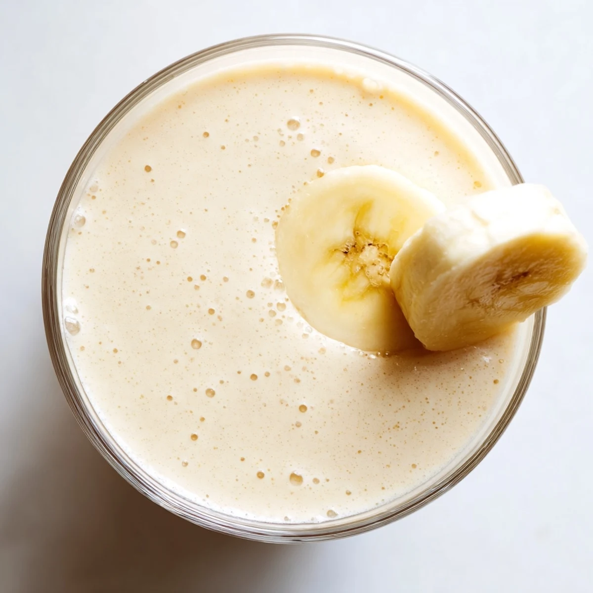 Thick protein-packed Greek yogurt banana smoothie blended with ice and drizzled with honey