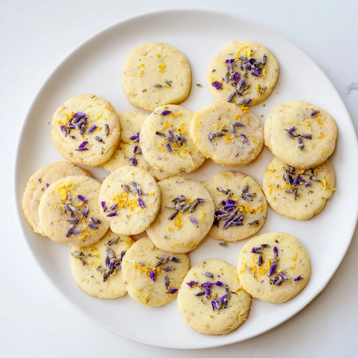 Golden lemon lavender cookies arranged on a cooling rack with visible purple lavender buds