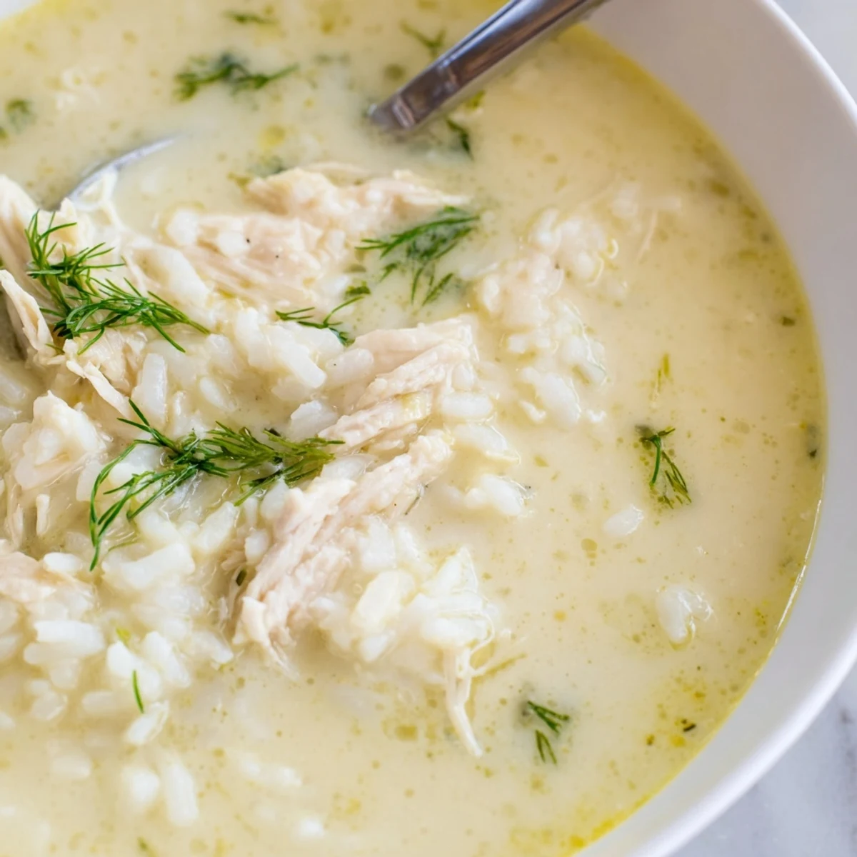 Steaming Avgolemono Greek lemon chicken soup with silky egg-lemon broth, tender chicken pieces, and white rice.
