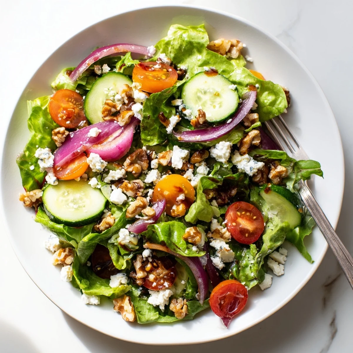 Vibrant spring mix salad featuring cucumber, red onion, and tangy balsamic honey dressing in a white serving bowl