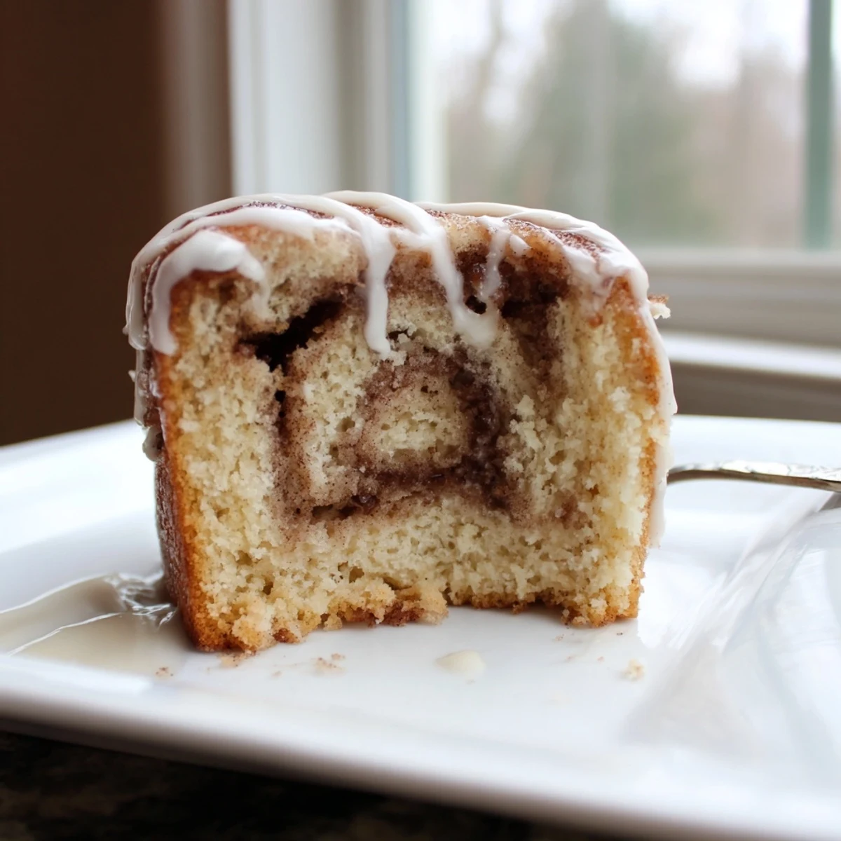 Soft baked cinnamon roll cake featuring marbled cinnamon sugar swirls under silky icing