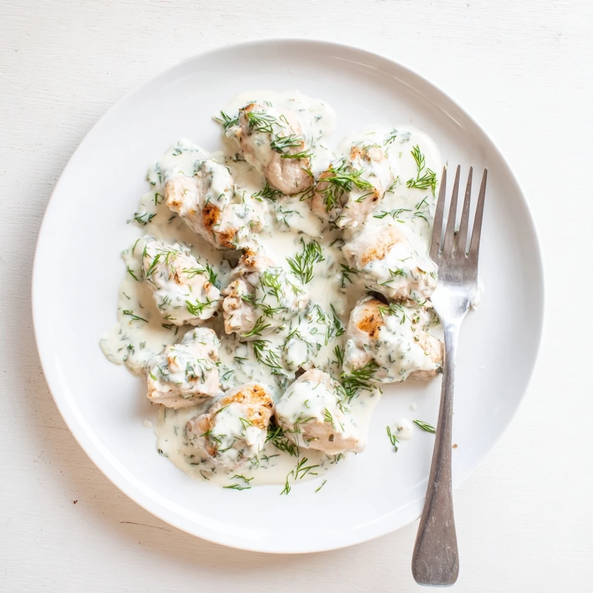 Golden brown chicken breasts resting in a velvety white dill cream sauce with fresh herb garnish