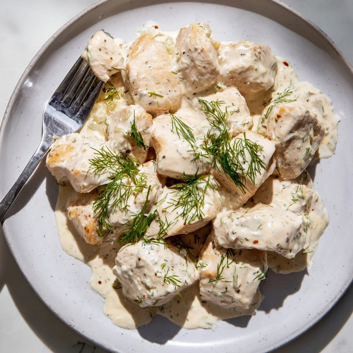 Tender seared chicken simmering in rich garlic dill sauce served over buttered noodles