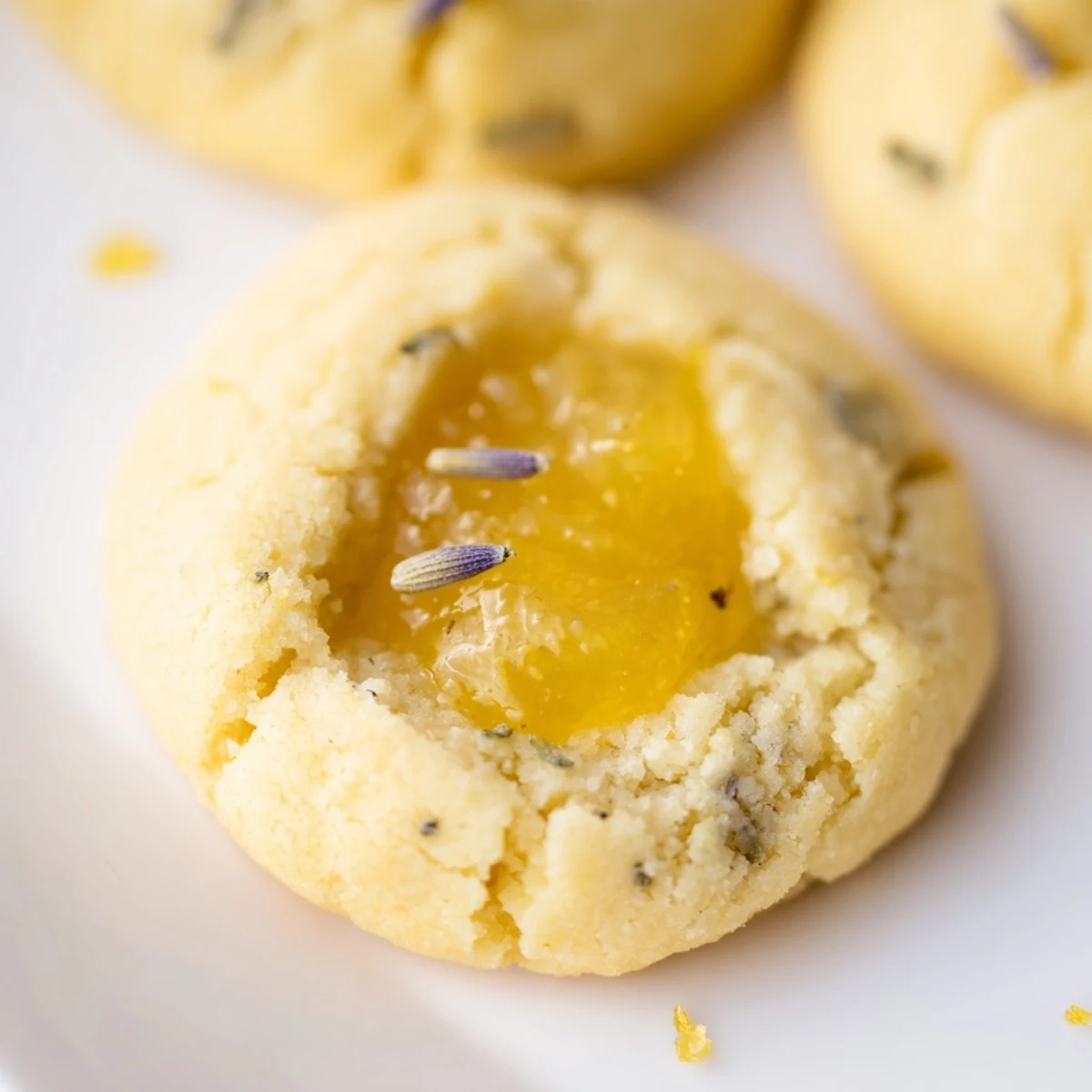 Close up of freshly baked lemon lavender thumbprint cookies topped with glossy lemon curd filling