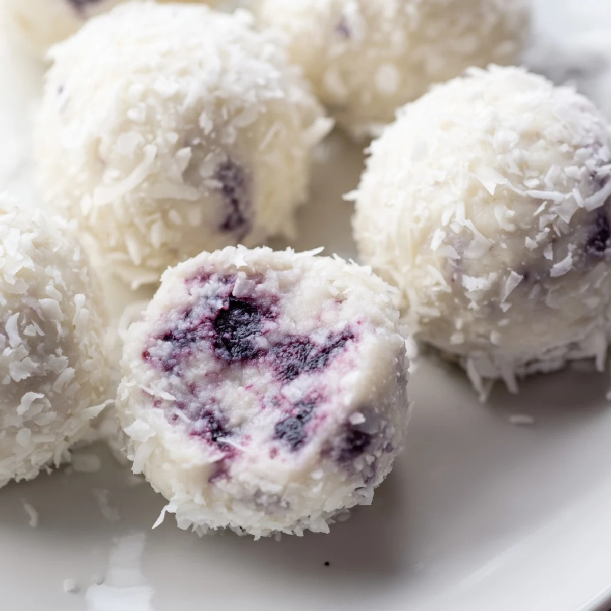 Fresh blueberry cheesecake protein bites arranged on parchment paper, ready for refrigeration.