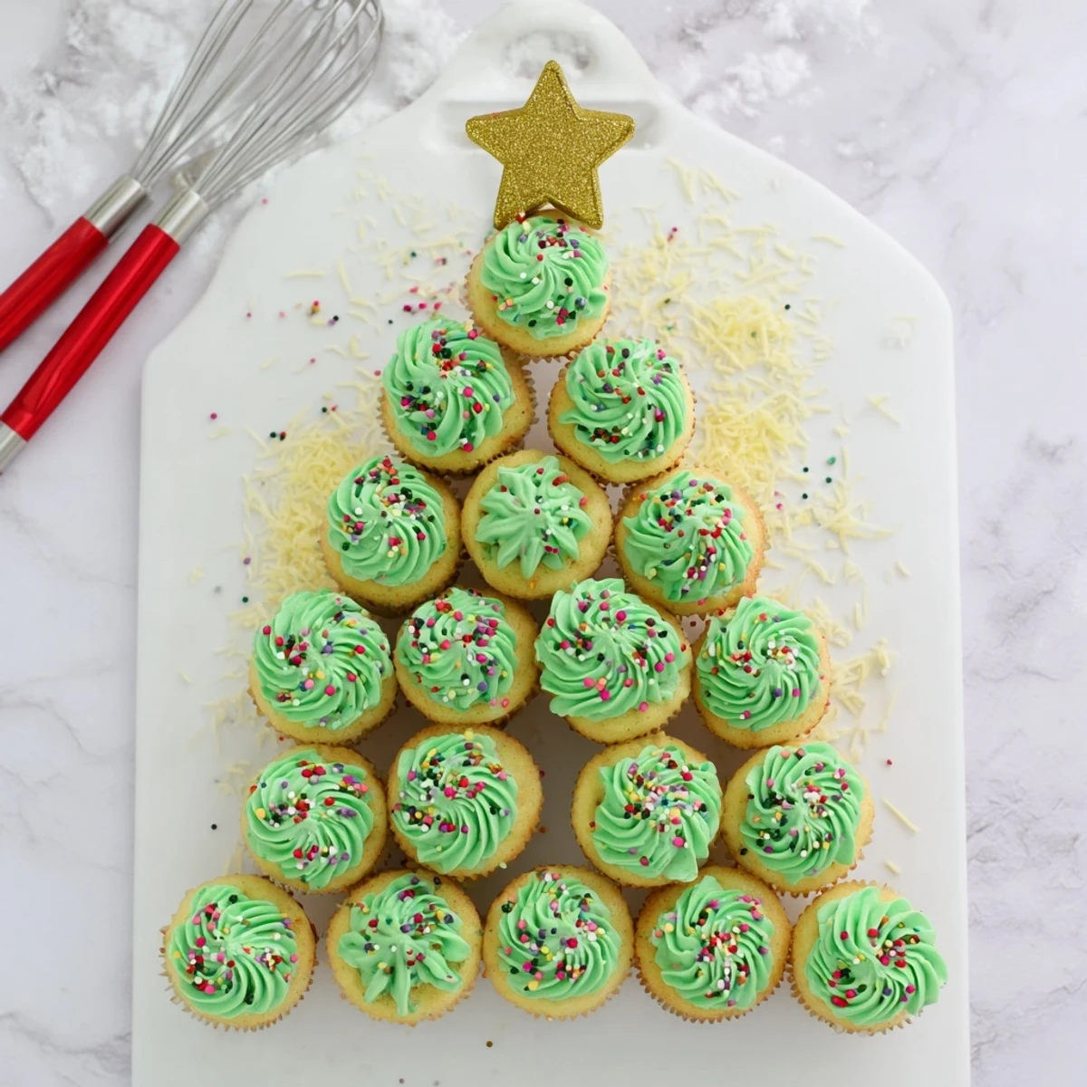 Holiday dessert display showcasing a cupcake Christmas tree topped with gold star and multicolored candy ornaments