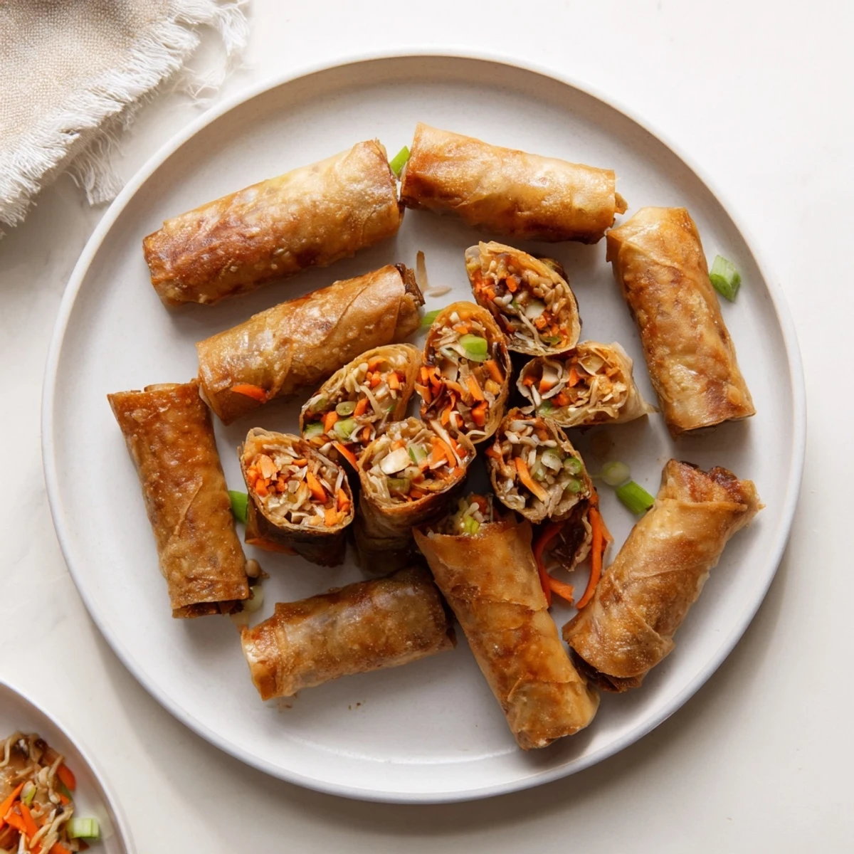 Golden crispy rice paper spring rolls with colorful vegetable filling on white plate