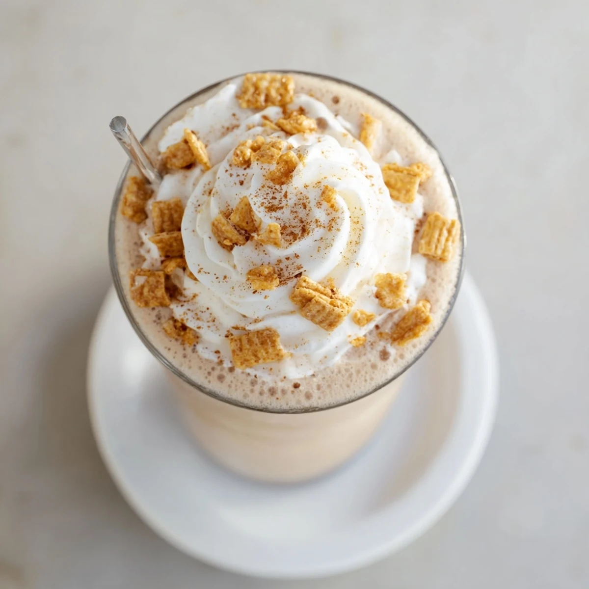 Tall glass of creamy Cinnamon Toast Crunch Frappe topped with whipped cream and cereal pieces
