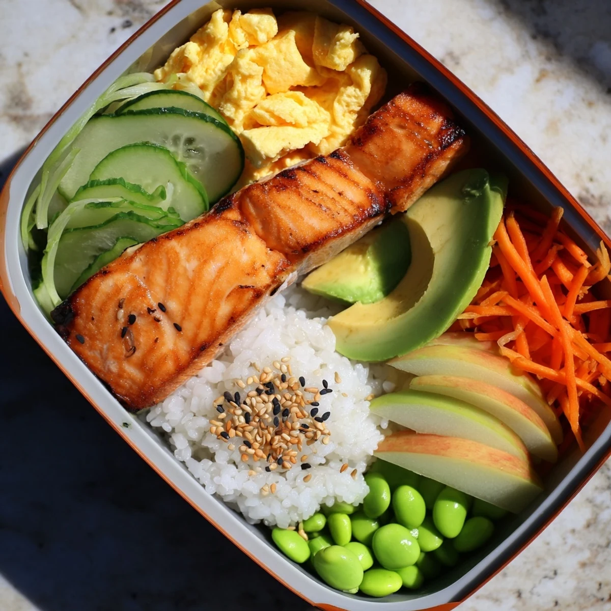 Colorful Japanese breakfast bento box featuring grilled fish and fresh seasonal fruit slices