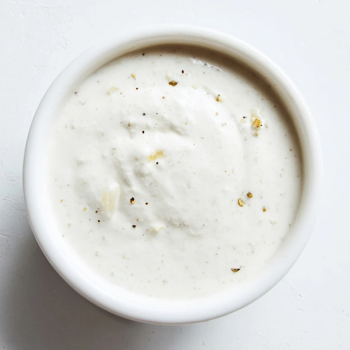 Creamy chicken shawarma garlic sauce in white bowl with olive oil drizzle