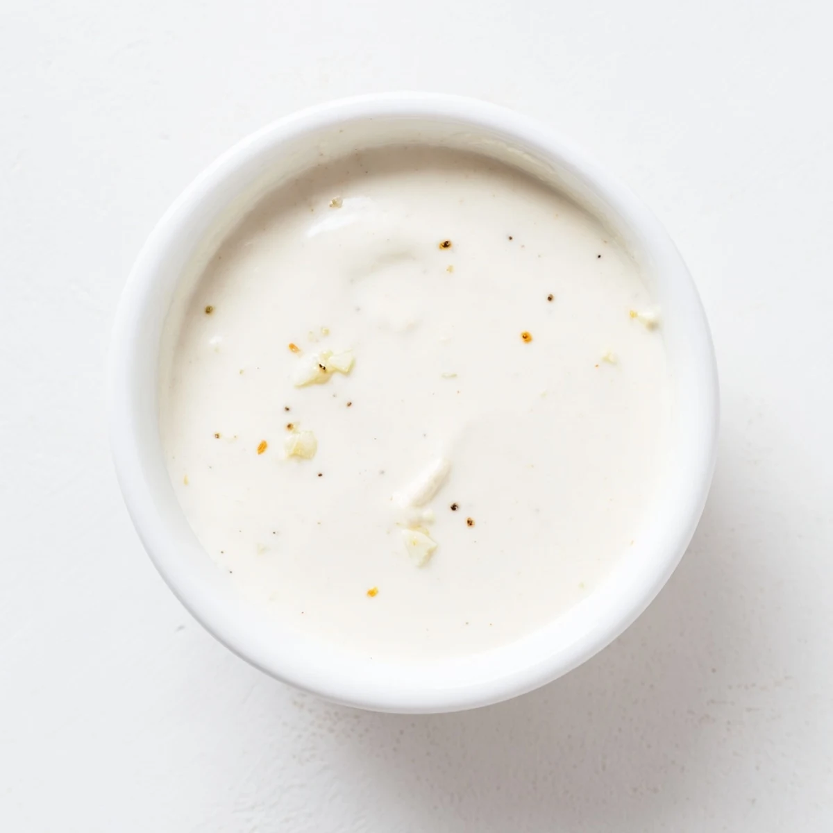 Close up of tangy garlic sauce topped with cumin and fresh parsley