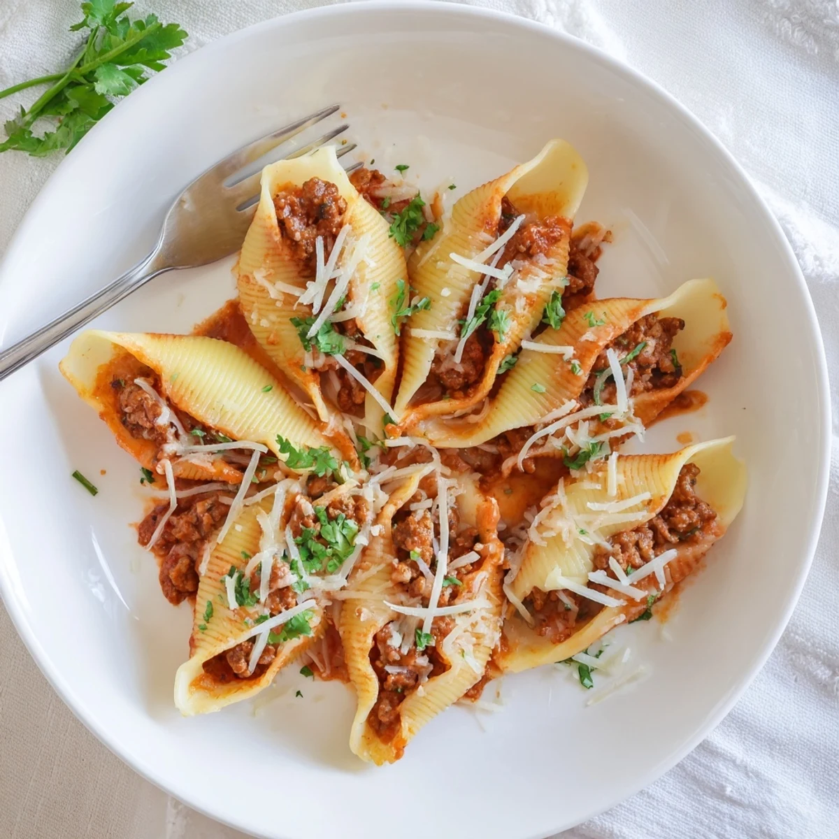 Baked creamy beef stuffed shells arranged in a white ceramic baking dish with bubbly mozzarella parmesan topping and rich marinara sauce
