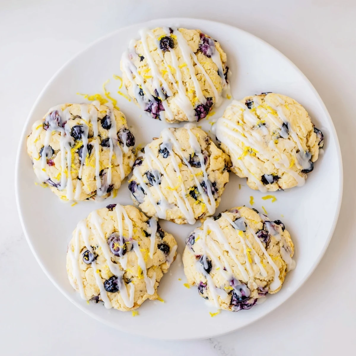 Soft lemon blueberry cheesecake cookies drizzled with white glaze on cooling rack