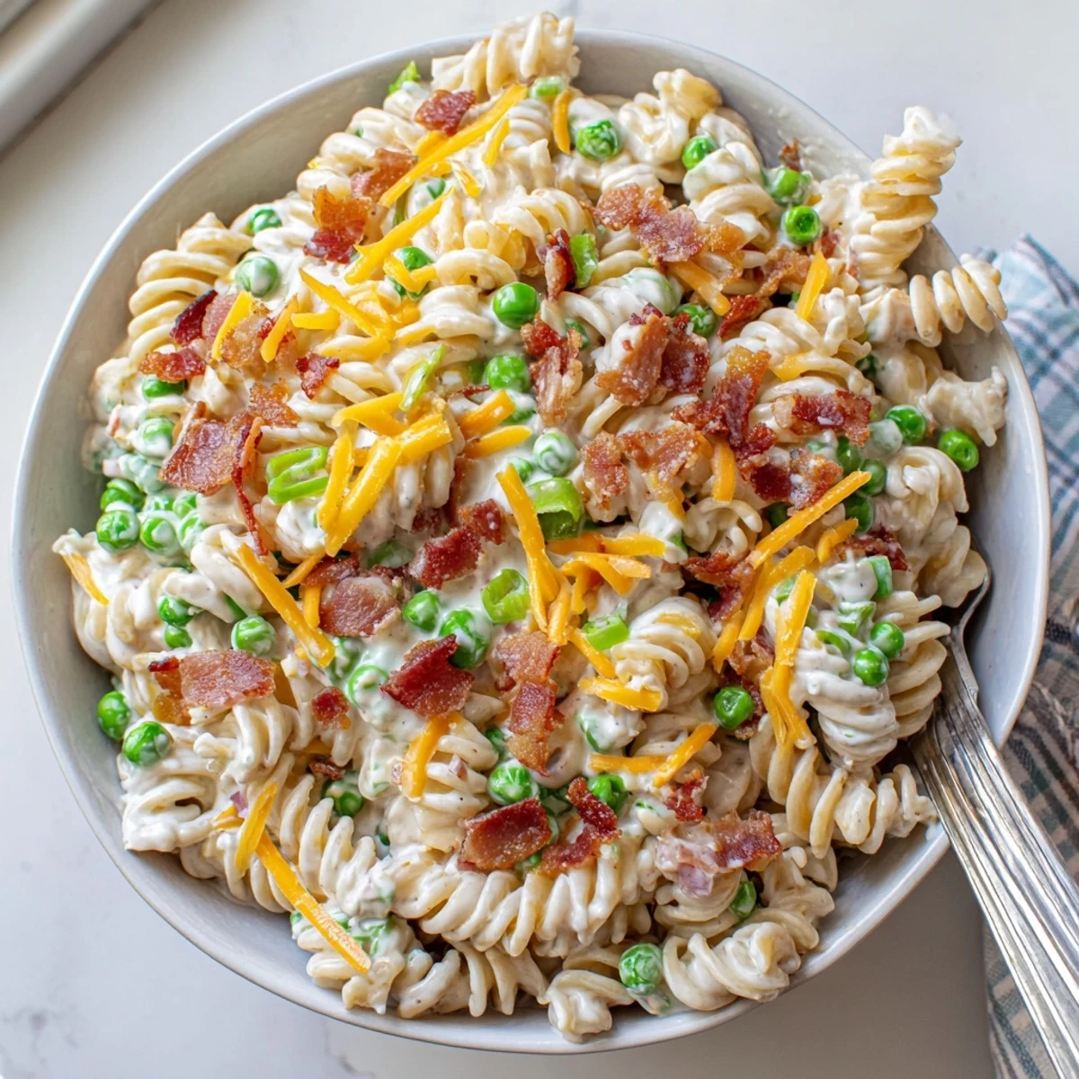 Bacon ranch pasta salad topped with green onions and chilled for serving