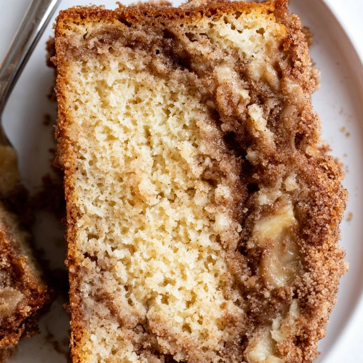 Golden slice of snickerdoodle banana bread with a cinnamon-sugar swirl on a white plate