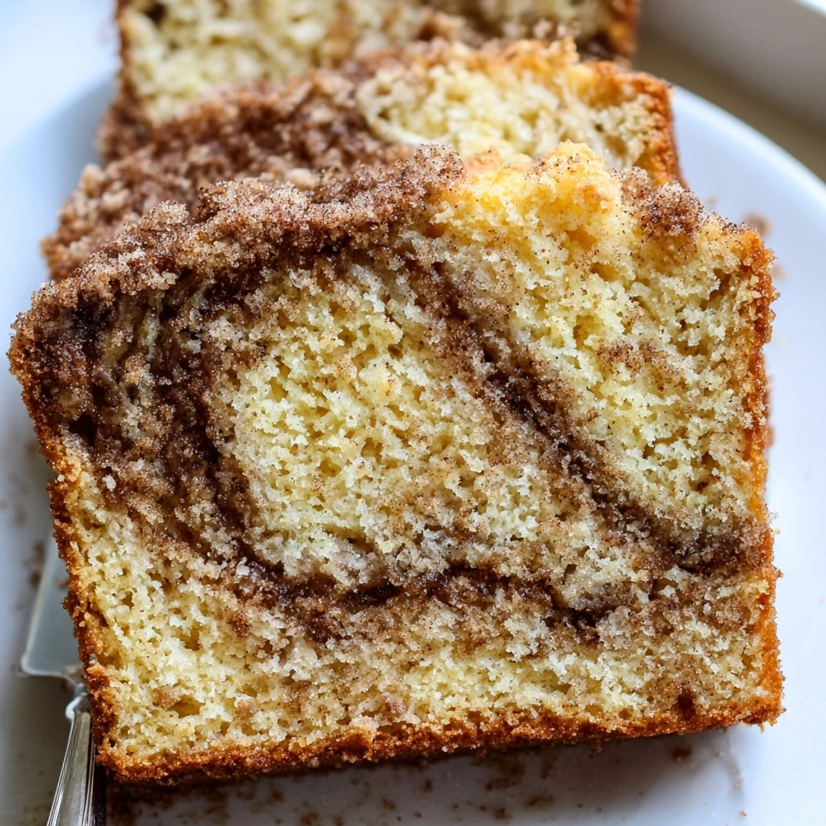 Warm snickerdoodle banana bread loaf sliced on a wire rack with marbled cinnamon topping